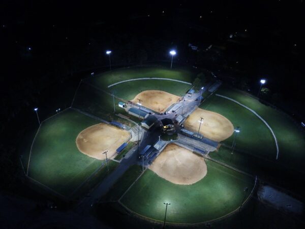 A baseball field with many players at night.