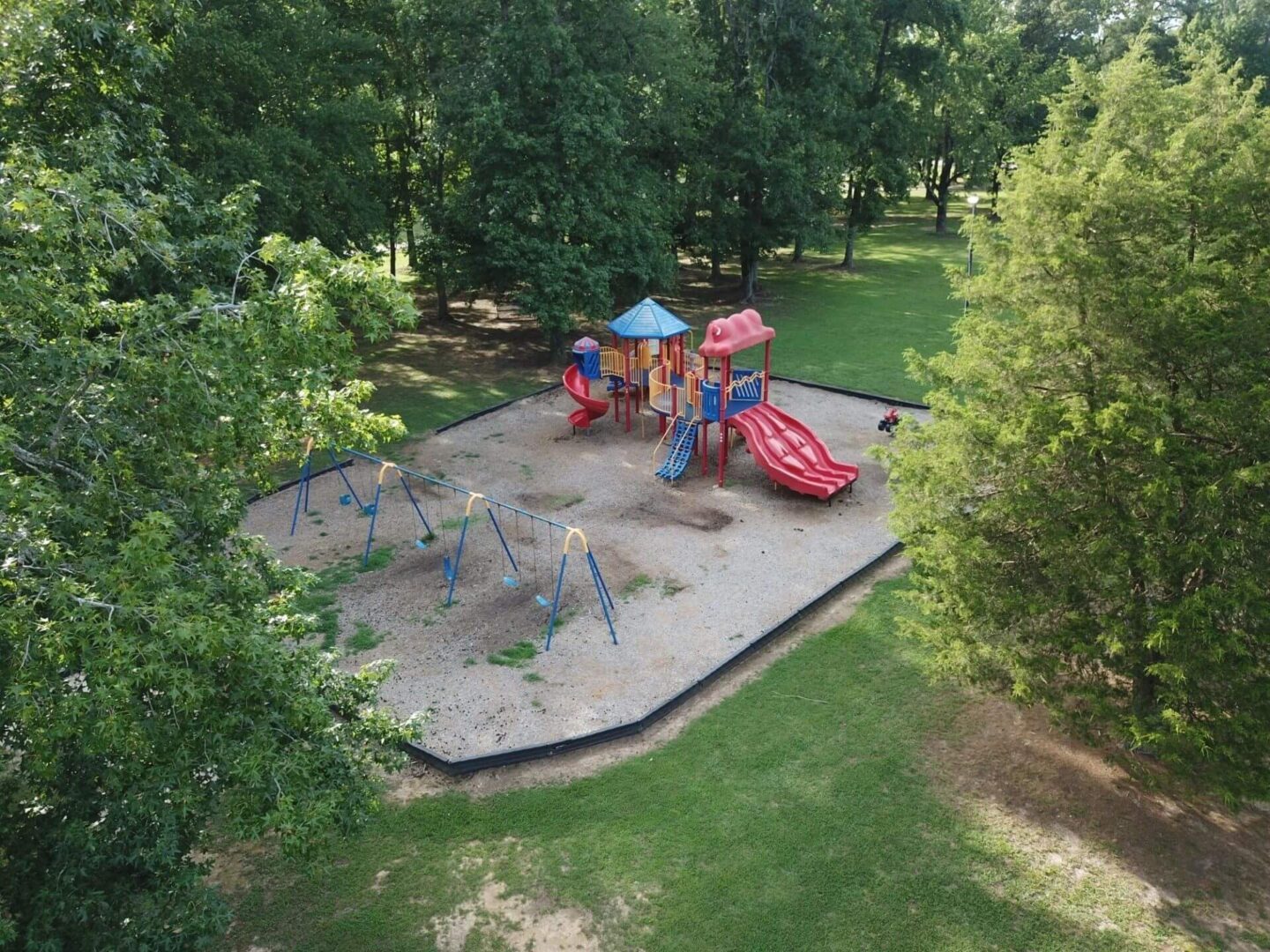 A playground with trees and grass in the background.